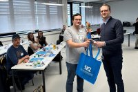TZQ-Leiter Christoph Kreutz (rechts) übergibt den ersten Teilnehmern in den neuen Räumlichkeiten ein Willkommenspräsent