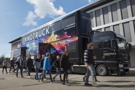 Der InnoTruck des Bundesforschungsministeriums in der Außenansicht mit einer Schülergruppe