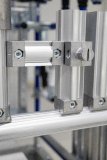 Verschiedene Ausführungen des Aluminium-Vierkantprofils 28 × 28 mm veranschaulichen die unterschiedlichen Profilvarianten und Verbindungsmöglichkeiten des Systems. Über passende Verbinder werden die Profile untereinander sowie mit einem Aluminium-Rundrohr verbunden. Ein separat dargestellter Verbinder gibt zusätzlich Einblick in die Verbindungstechnik und zeigt dessen Aufnahme im Profil.
