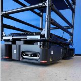 Das Bild zeigt eine mobile Transportlösung mit einem autonomen Fahrroboter von wheel.me, kombiniert mit einer modularen Konstruktion aus dem BeeWaTec Rohrstecksystem aus Stahl. Der Aufbau verfügt über mehrere Ablageflächen, die zur sicheren Aufnahme von Paketen oder Materialien dienen. So können Güter flexibel und effizient von A nach B transportiert werden, ohne feste Transportwege oder manuelle Fördertechnik.