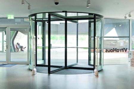 Karusselltüranlage GEZE TSA 325 NT mit durchgängigen Ganzglasflächen ohne Mittelsäule und barrierefreie Automatik-Fassadendrehtür mit der Antriebseinheit Slimdrive EMD F-IS in "7-cm-Optik" als Flucht- und Rettungswegtür