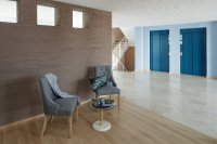 Die Aufenthaltsbereiche mit den Aufzügen sind je Geschoss individuell gestaltet und laden Bewohner und Gäste zum Verweilen ein. Hier der Aufzugkubus im Farbton 3D Lazur 180 mit Aufzugtüren in RAL 5001, die Akzentwand im Farbton 3D Siena 35 / Bild: Caparol Farben Lacke Bautenschutz/Alexandra Lechner