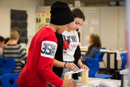 Verschiedene Experimentierstationen laden Schüler ein, selbst aktiv zu werden. Hier wird gerade ausprobiert, wie stabil eine Brücke aus Papier sein kann / Foto: IJF/Tamara Hegedüs