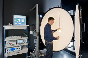 Wechsel einer Lichtquelle in einer Ulbricht-Kugel in einem TÜV SÜD Labor. In einer Ulbricht-Kugel wird der Gesamtlichtstrom sowie die spektralen Eigenschaften einer Lichtquelle und gleichzeitig die elektrische Leistungsaufnahme gemessen