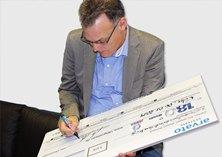 Mit Freude unterzeichnet Dr. Manfred Heinen, Geschäftsführer der arvato Systems S4M GmbH, den symbolischen Scheck, der dank sehr engagierter Mitarbeiter zustande gekommen ist.