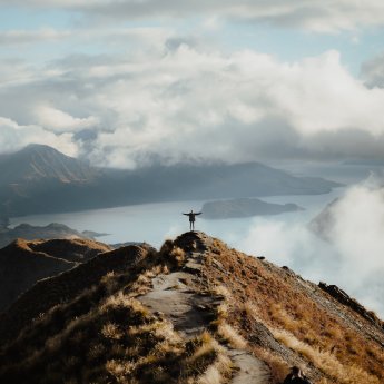 man-with-hands-wide-open-standing-top-mountain-enjoying-incredible-view-lake.jpg