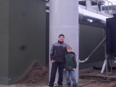 Jan Kroll mit seinem Sohn vor der Biogas Anlage, die der Unternehmen der e2m zur Vermarktung anvertraut hat