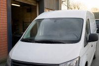Transporter eines Handwerksbetriebs mit Ortungsgerät hinter der Windschutzscheibe. Ein weißer Transporter steht am frühen Morgen vor einer Werkstatt, hinter der Windschutzscheibe ist ein kleines Ortungsgerät sichtbar, im Hintergrund unscharf weitere Fahrzeuge. Symbolbild zur Ortung von Firmenfahrzeugen und zum Umgang mit Standortdaten von Beschäftigten.