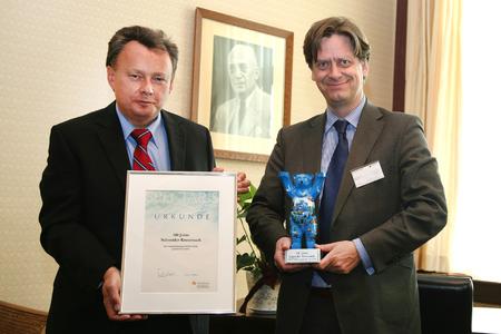 Dr. Tobias Weiler, Geschäftsführer des Deutschen Industrieverbandes Spectaris, übergibt einen Ehrenbären an den Geschäftsführer der Schneider-Gruppe Dr. Josef Staub.