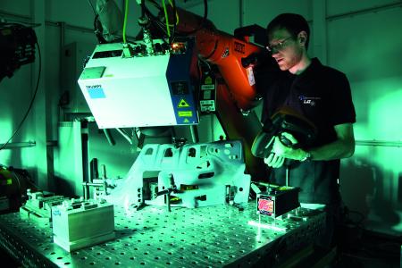 Markus Hofele, Doktorand am LaserApplikationsZentrum, richtet in der neuen Roboterzelle den 3D-Scanner aus. Der Bearbeitungskopf führt den Laserstrahl mittels beweglicher Spiegel über das Werkstück, Fotonachweis: © Hochschule Aalen/ Gaby Keil