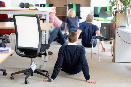Was machen die denn da im Büro? Zum gesünderes Verhalten am Arbeitsplatz gehört auch die eine oder andere Fitnessübung.