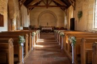 Leeres Kirchenschiff mit weiß geschmückten Bankreihen und Blumengestecken im Mittelgang