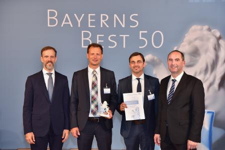 Freuen sich über die Anerkennung: Christoph Hitzler (2. v. li.) und Wolfgang Gürtner (3. v. li.) bei der festlichen Preisverleihung mit dem Bayerischen Wirtschaftsminister Hubert Aiwanger (re.) und Juror Dr. Christian Escher (li.) in Oberschleißheim / Bild: © Studio SX HEUSER