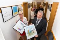 Die Leitende Verwaltungsbeamtin Iris Brincker und WEMAG-Kommunalbetreuer Bernd Halfkath (v.l.) haben im Amt Lützow-Lübstorf eine von der WEMAG initiierte Cartoon-Ausstellung eröffnet (Foto: WEMAG/Rudolph-Kramer)