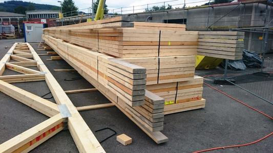 Korrekt gelagert: Nagelplattenbinder werden von GIN-Mitgliedsfirmen wettergeschützt vorgefertigt und richtfertig auf die Baustelle gebracht. Dort müssen die bis zu 35 m langen Tragwerkselemente nach dem Abladen vom LKW durchbiegungsfrei gelagert werden. Bei der Geschäftsstelle der Gütegemeinschaft Nagelplattenprodukte e.V. (GIN) in Ostfildern ist eine Informationsschrift mit Hinweisen zur korrekten Zwischenlagerung auf Baustellen erhältlich. (Foto: Meilinger/GIN, Ostfildern; www.nagelplatten.de)