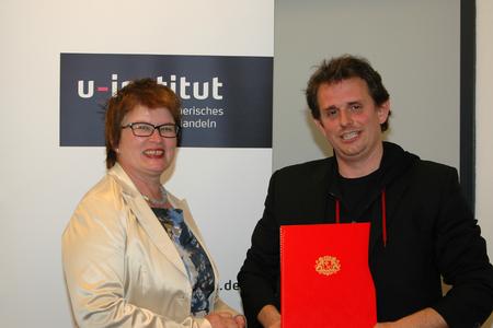 Rektorin Prof. Dr. Karin Luckey überreicht Christoph Backes die Einrichtungsurkunde für das u-institut