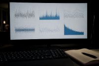 Bildschirm mit mehreren Kursverläufen in einem abgedunkelten Raum