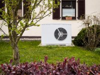 Luft-Wasser-Wärmepumpe im Garten vor einem Wohnhaus