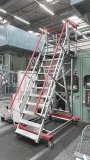 Die HYMER-Podestreppe 2230 verschafft einen sicheren Zugang bei Wartungsarbeiten an einer Hydraulikpresse für Karosserieteile. Das fahrbare Modell mit stirnseitiger Überkragung wurde speziell für den Bedarf in einem Hamburger Werk eines bekannten deutschen Auto-mobilisten anpasst. / Bildquelle: HYMER-Steigtechnik 