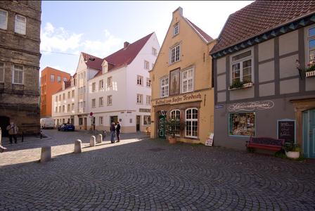 Das dreigeschossige Wohn- und Geschäftshaus (links) bildet zusammen mit dem Gasthof zum Kaiser Friedrich für die vom Markt kommenden Besucher das Eingangstor zur Gassenwelt des Schnoorviertels
