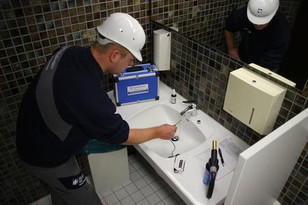 Mitarbeiter prüft Trinkwasser auf Legionellen-Belastung