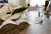 Kassenbon liegt neben einer Einkaufstasche auf einem Küchentisch