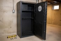 Geöffneter Stahlschrank in einem Kellerraum mit leeren Halterungen und einem Prüfsiegel an der Innenseite der Tür