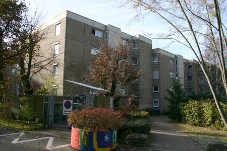 Die Wohnanlage zeigte sich vor der Neugestaltung der Fassaden in einem tristen Grau. Nur der bemalte Pflanzkübel im Vordergrund erinnerte noch an das Potenzial der Farbe.