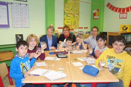 Was passiert mit Kies oder Salz im Wasser: Kinder der Klasse 3 der Johann-Lemmerz-Schule untersuchen die Veränderung von unterschiedlichen Feststoffen in Wasser / Die Gäste zeigen sich von den Hypothesen der Kinder beeindruckt / (v.l. Christian Brand, Bildungs-Stiftung der Kreissparkasse Köln, Gudrun Börter, Regionaldirektorin der Kreissparkasse Köln, Sven Haack, Schulleiter / Namen der Kinder v.l.: Mohammed, Antonia, Leon R., Alina, Boran, Leon M