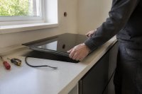 Handwerker setzt ein Kochfeld in eine Küchenarbeitsplatte ein