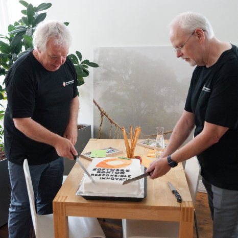 Peter Schubert und Martin Mosetter schneiden die Geburtstagstorte an.png