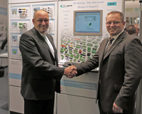 Jens-Uwe Henkel, Product Marketing COMBICON bei Phoenix Contact und Christian Baumgärtner, Geschäftsführer TraceParts GmbH, auf dem Phoenix Contact Messestand mit der 3D-Online-Lösung von TraceParts im Hintergrund.
