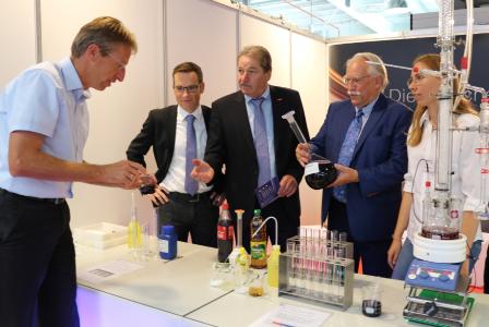Messerundgang: Dietmar Niedziella (v.l), Leiter IHK-Berufsbildung, Achim Hofmann, stv. HWK-Hauptgeschäftsführer mit HWK-Vizepräsident Kurt Georg Schreiber, IHK-Präsident Prof. Dr. Dr. h.c. Harald Unkelbach und Lisa Uhlmann, Chemielaborantin bei der Brüggemann Gruppe / © IHK