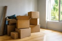 Gepackte Umzugskisten vor einer leeren Wohnung mit offenem Fenster