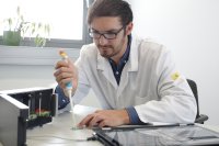 Alexander Hofmann mit einem optoelektronischen CMOS-Biochip auf einer Cartridge und einem zugehörigen Testsystem für Untersuchungen zu seiner Dissertation “CMOS-Biochip-System zur optischen Detektion und Quantifizierung von Analyten”.