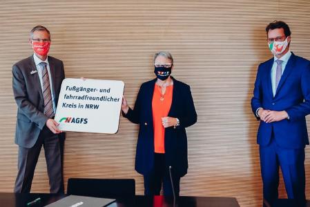 Landrat im Kreis Gütersloh Sven-Georg Adenauer, AGFS-Vorstand Christine Fuchs und NRW-Verkehrsminister Hendrik Wüst mit dem neuen Ortsschild, das die Mitgliedschaft des Kreises Gütersloh in der AGFS auch nach außen hin dokumentiert / Foto: VM / Anja Tiwisina