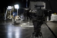 Filmkamera auf einem Stativ in einer abgedunkelten Halle