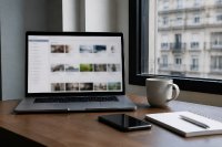Schreibtisch mit Laptop, auf dem eine unscharfe Übersicht vieler Anzeigenkacheln geöffnet ist