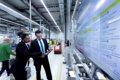 Optimierte Prozesse und Abläufe durch Digitalisierung: WITTENSTEN-Mitarbeiter in der Fellbacher Produktion in Abstimmung an der elektronischen Plantafel