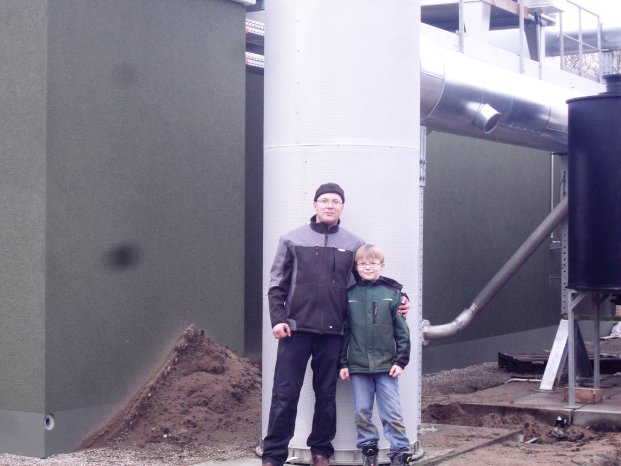 Jan Kroll mit seinem Sohn vor der Biogas-Anlage, die der Unternehmen der e2m zur Vermarktun.JPG