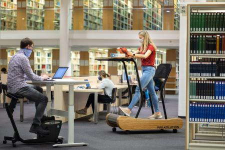 Studentin Luisa Frech und Georg Peter vom Studentischen Gesundheitsmanagement testen in der Universitätsbibliothek der TU Ilmenau die dynamischen Arbeitsplätze (© TU Ilmenau/Michael Reichel
