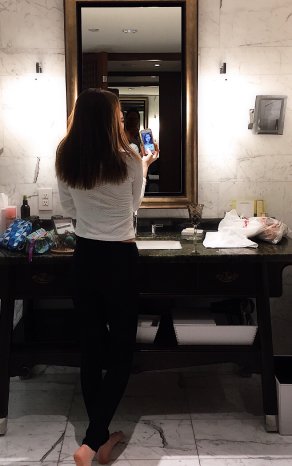 young-girl-standing-in-a-hotel-bathroom-and-taking-6YKSNJK.jpg