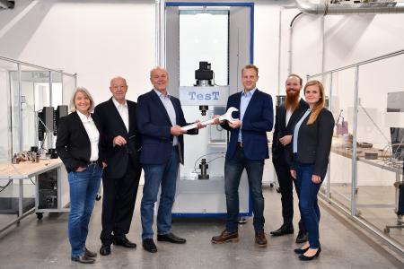 The founding generation (Therese Havemann, Klaus Havemann, Dr. Axel Hunsche) of German testing machine manufacturer TesT passing the baton to the succeeding generation (Jan Havemann, Arne Havemann, Julia Kiewitter (neé Hunsche)) in the form of a spanner