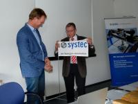Die Fahne der Systec GmbH in Münster wird künftig von Niederlassungsleiter Jan Leideman (l.) hochgehalten. Der scheidende Geschäftsführer Tilmann Wolter über-gab ihm die Leitung des Unternehmensstandorts im Rahmen einer kleinen Zeremo-nie. (Bild: Systec GmbH)