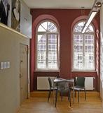 Die vergitterten Fenster, hier die Rundbogenfenster an der Stirnseite der Flure, erinnern an die frühere Nutzung als Gefängnis. Die Stirnseiten wurden in der Kennfarbe des jeweiligen Stockwerks gestaltet, Foto: Caparol Farben Lacke Bautenschutz/Martin Duckek