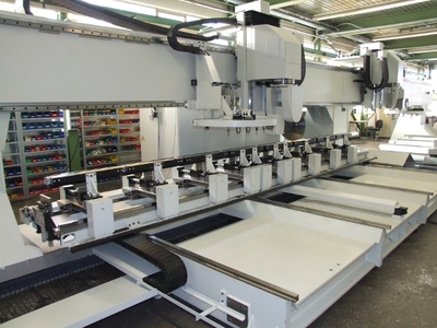 Die fast 15 m lange EiMa-Sondermaschine mit 2 Spindelköpfen. Ihre Fahrständer können auf der X-Achse bis zu 100 m/min beschleunigen. Für Bewegungen auf der Y-Achse wird der ganze Maschinentisch bewegt. Beim Beladen fährt der Tisch 3 m nach vorne