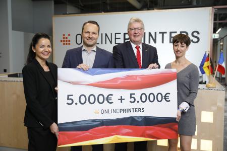(v.l.) Cécile Assayag-Zimmermann, Marketing Managerin bei Onlineprinters, Dirk A. Müller, CFO der Onlineprinters-Gruppe, und Cécile Delorme, Leitung Brand Management (r.), übergeben Honorarkonsul Dr. Matthias Everding (2. v.r.) einen symbolischen Scheck in Höhe von insgesamt 10.000 Euro - die Hälfte davon fließt in den Wiederaufbau der Kathedrale Notre-Dame, die anderen 5.000 Euro werden für den deutsch-französischen Schüleraustausch verwendet (Copyright: Onlineprinters GmbH)