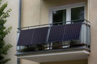 Zwei Solarmodule hängen an einem Balkongeländer eines Mehrfamilienhauses
