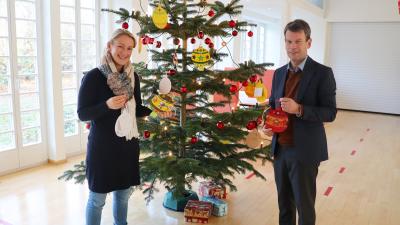WEMAG-Vorstand Caspar Baumgart und Demmlerhaus-Leiterin Carolin Schulz bringen die Karten mit den Wünschen der Kinder am Weihnachtsbaum im WEMAG-Speisesaal an / Foto: WEMAG/Nele Reiber