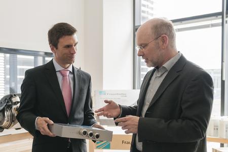 Der stellvertretende IISB-Institutsleiter Prof. Dr. Martin März (rechts), Leiter des Geschäftsbereichs Leistungselektronik, informiert Staatssekretär Stefan Müller über die Leistungsfähigkeit moderner leistungselektronischer Wandler (Foto: Fraunhofer IISB).